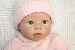 Gros plan d'une poupée reborn réaliste avec cils à la main et bonnet en tricot rose