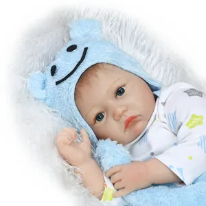 Close-up of lifelike reborn baby doll face with blue eyes and bear-themed plush hat