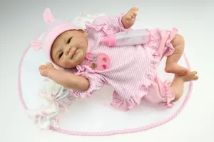 Realistic reborn baby doll set with pink striped outfit, hat, bottle, and soft cloud pillow