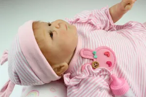 Close-up of lifelike reborn baby doll in pink striped outfit with a mini bottle