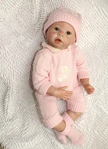 Vue détaillée d'une poupée reborn réaliste en tenue tricotée rose sur tapis peluche