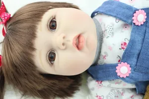 Close-up of realistic reborn doll face with brown eyes and floral dress details