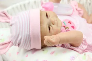 Detailed view of reborn baby doll in pink striped outfit with matching rabbit ear hat