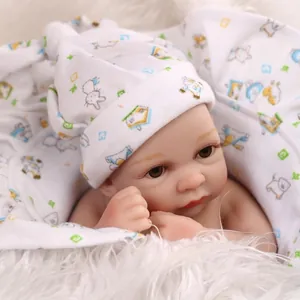 Close-up of a lifelike mini reborn baby doll in soft white printed cotton outfit