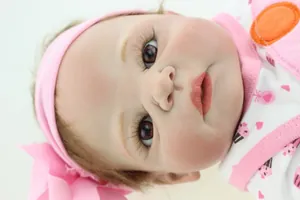 Close-up of realistic newborn doll with brown eyes and long eyelashes wearing a pink headband
