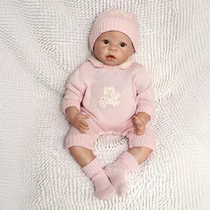 Poupée nouveau-né réaliste en tenue tricotée rose avec broderie ours sur couverture blanche