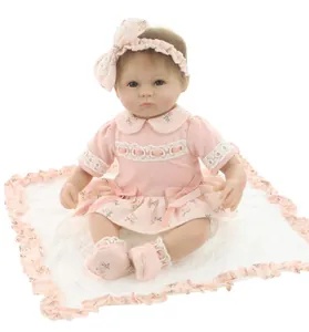 Close-up of realistic newborn baby doll in pink floral dress and bow headband