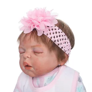 Gros plan sur un bandeau à fleur en mousseline rose sur une poupée Reborn endormie