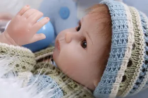 Close-up of lifelike newborn doll with realistic brown hair and knit outfit