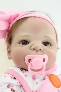 Close-up of lifelike baby doll with pink flower headband and heart print outfit