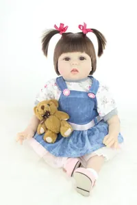 Detailed realistic reborn baby doll with pigtails holding a brown plush teddy bear