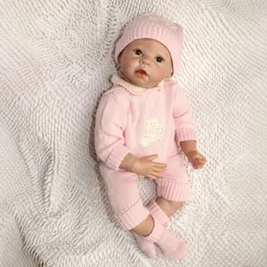 Poupée nouveau-né réaliste en tenue tricotée rose sur fond en peluche blanc