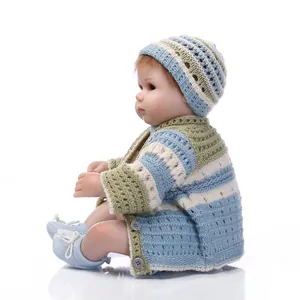 Close-up of a lifelike reborn doll wearing a striped handmade knit cardigan and hat