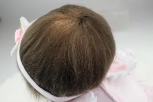 Macro view of brown rooted hair and lace floral headband on the lifelike reborn doll