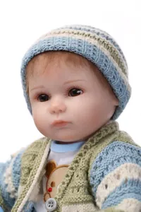 Close-up of realistic baby doll face with knitted hat and detailed facial features