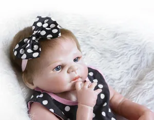 Close-up of lifelike baby doll with blue eyes wearing a black polka dot headband and dress