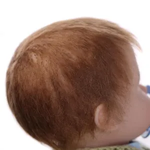Detailed macro view of hand-rooted brown hair on soft vinyl realistic reborn baby doll