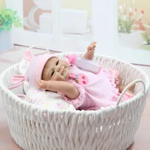 Lifelike reborn baby doll in pink stripe outfit resting in a woven basket