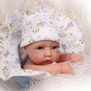 Realistic reborn baby doll in a white cartoon print swaddle blanket on plush background