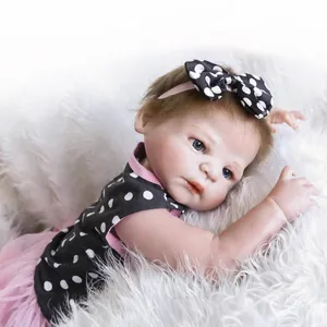 Realistic reborn baby doll in polka dot dress lying on a soft white plush rug