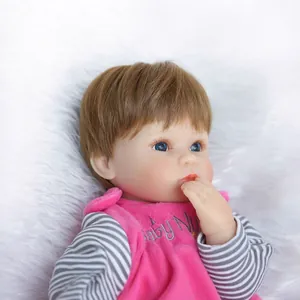 Bambola reborn realistica con occhi azzurri e abito in velluto rosa su tappeto