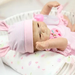 Realistic sleeping reborn baby doll in pink rabbit outfit and woven basket cradle