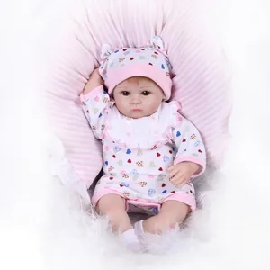 Poupée bébé réaliste en pyjama à cœurs roses reposant sur un coussin doux rayé
