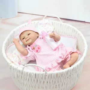 Realistic newborn baby doll in pink striped outfit resting in a cozy woven basket