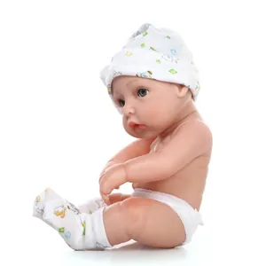 Detail view of realistic baby doll in white bird print outfit and cap on white background