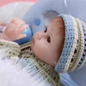 Realistic reborn baby doll with brown hair in a green and beige knit sweater