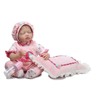 Close-up of sleeping reborn baby doll in pink floral outfit with a mini bottle