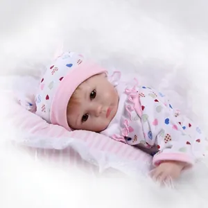 Poupée nouveau-né réaliste avec pyjama à cœurs et bonnet sur oreiller rose