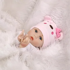 Bambola reborn realistica con cappello rosa da animale su morbido peluche bianco