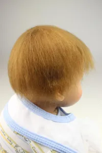 Detailed close-up showing the realistic rooted light brown hair of a silicone reborn baby doll
