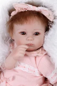 Close-up of realistic newborn doll with brown eyes and pink knit lace outfit