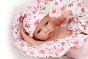 Close-up of soft reborn baby doll with gray-blue eyes and pink elephant print outfit