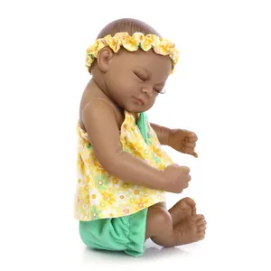 Detail of a sleeping newborn doll with dark skin wearing a yellow floral outfit