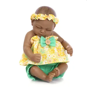 Detail of a realistic African newborn baby doll in floral yellow outfit sleeping peacefully