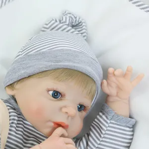 Realistic reborn baby doll with blue eyes and gold hair in gray striped outfit