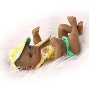 Deep skin mini twin baby doll in floral vest and yellow hat on white plush rug