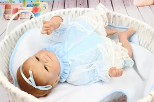 Détail d'une poupée reborn réaliste en tenue de dentelle bleue dans un panier tressé