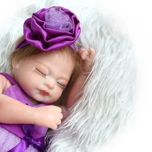 Realistic reborn baby doll in purple floral outfit sleeping on white plush background