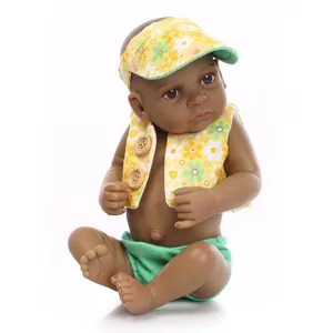 Lifelike black reborn baby doll wearing a yellow floral hat and vest on white background