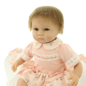 Realistic reborn baby doll in pink lace knitted dress with soft brown hair and eyes