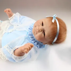 Poupée reborn réaliste fille avec cheveux roux et tenue en dentelle bleue sur coussin