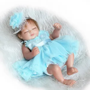 Realistic sleeping reborn baby doll in blue tutu dress on white faux fur background