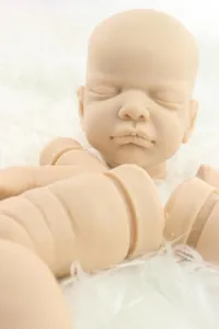 Detailed view of unpainted soft silicone reborn doll kit head and limbs on white fur