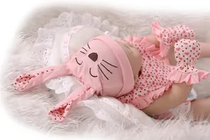 Detailed view of sleeping reborn baby doll in pink rabbit hat and heart print dress