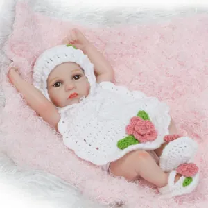 Mini poupée bébé réaliste avec tenue au crochet blanc sur fond en peluche rose