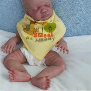 Realistic silicone reborn baby doll with honey bear bib and diaper on blue background